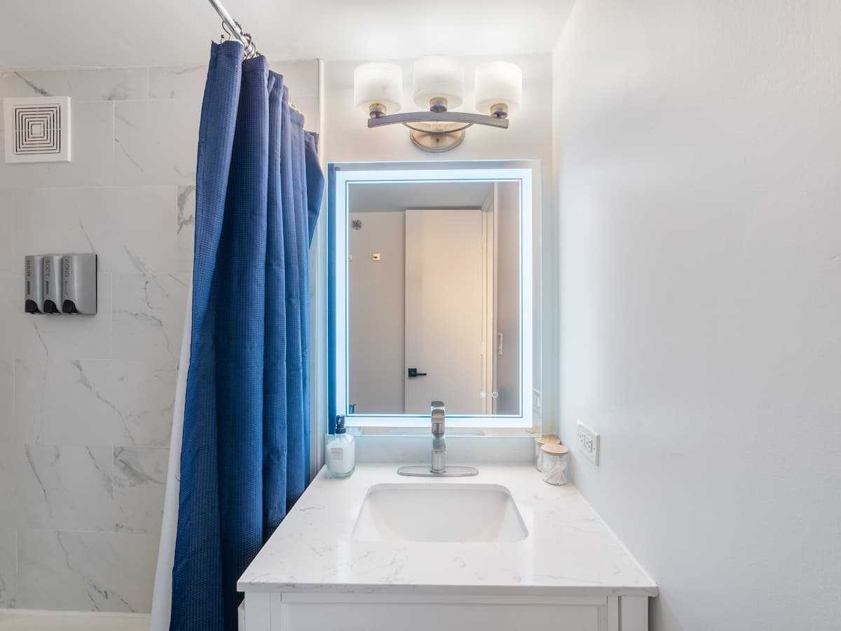 Bathroom vanity with a mirror and blue shower curtain