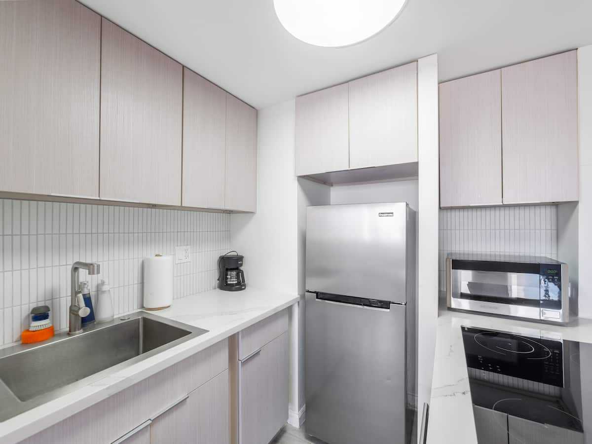 Kitchen sink, coffee maker, refrigerator, and cabinets