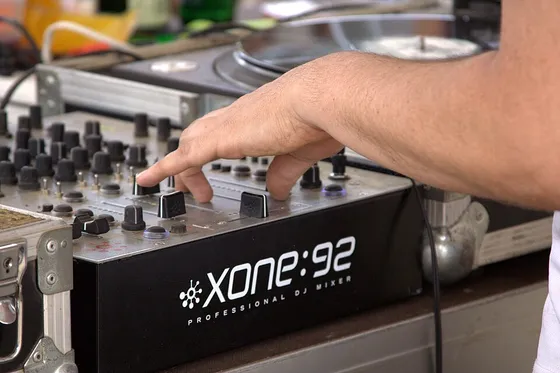 A DJ adjusting a mixer beside the turntables.
