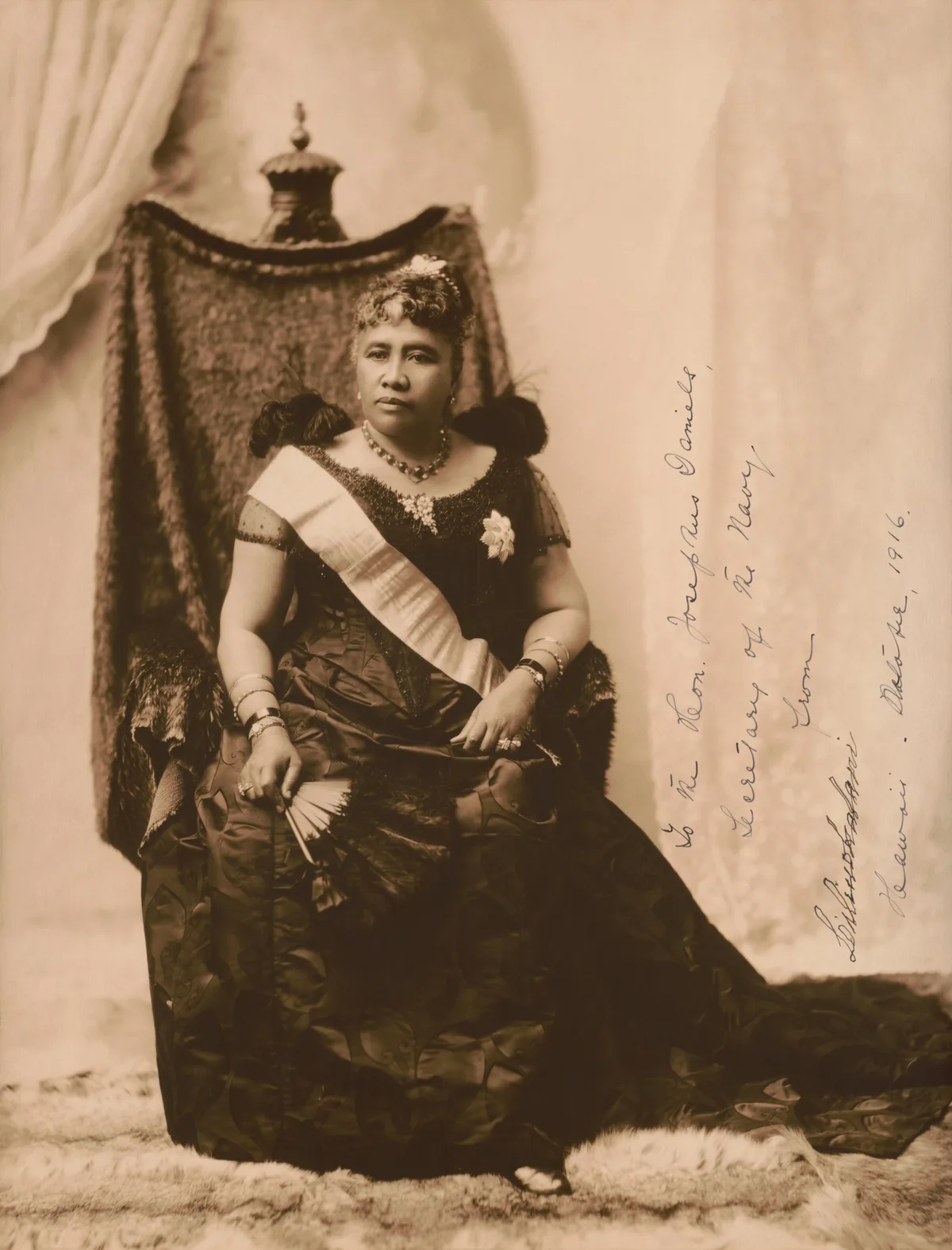 Queen Liliʻuokalani seated in a formal gown, in a portrait from about 1891.