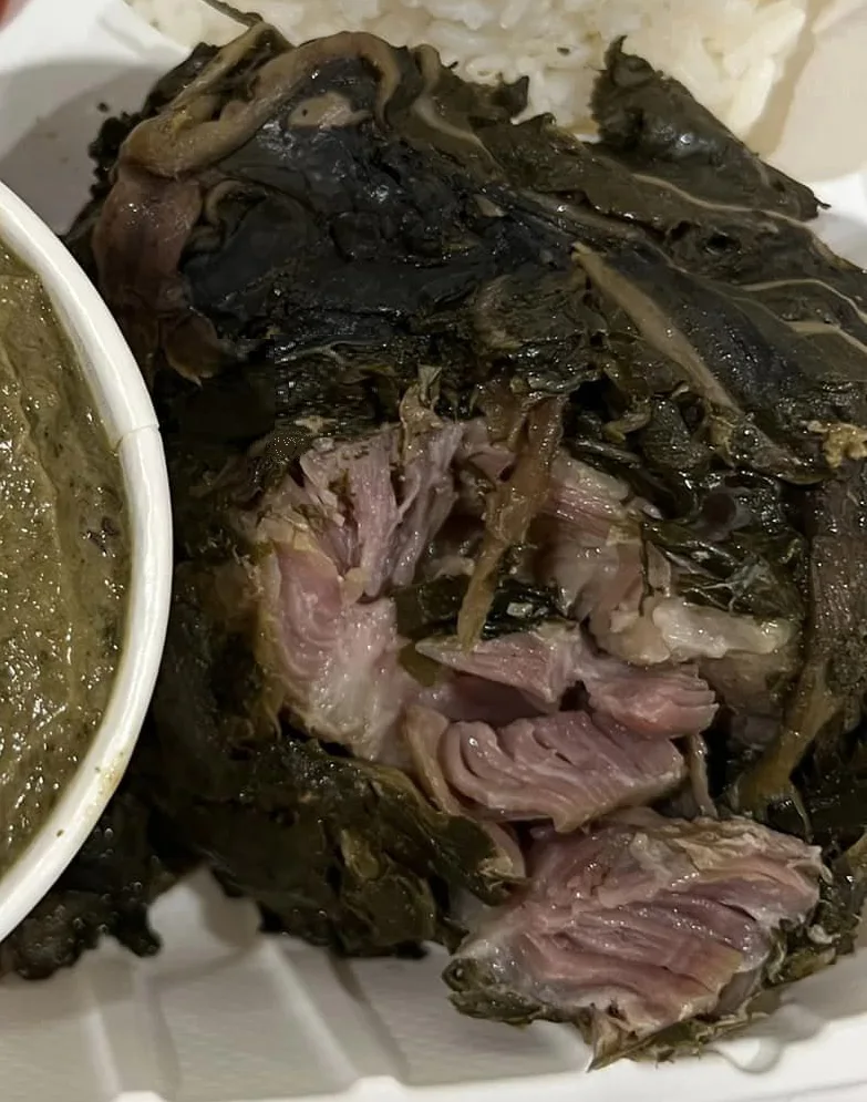 An opened laulau showing pork inside cooked taro leaves.