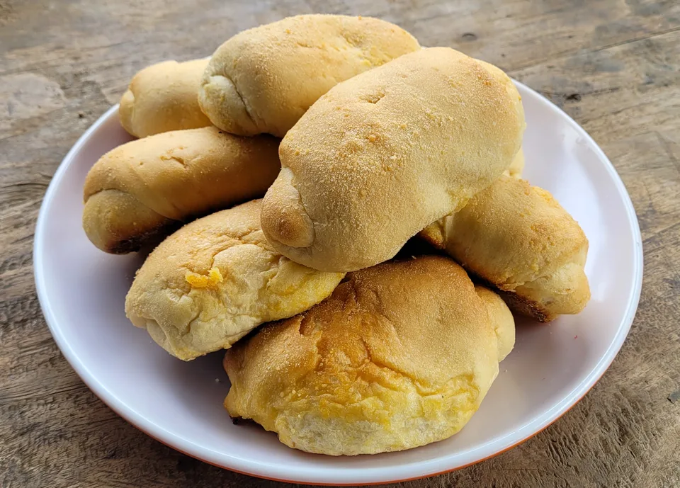 Golden Filipino Spanish bread rolls on a white plate.